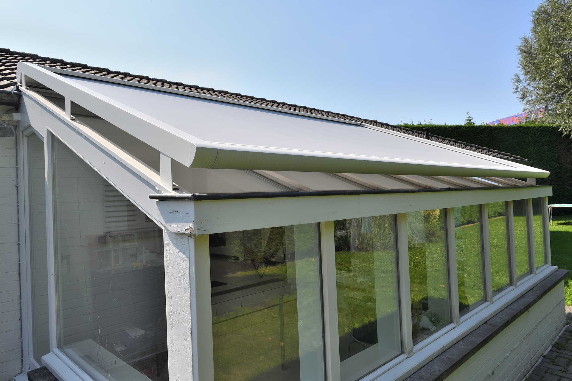 Brustor conservatory awning mounted above a sloped glass roof providing exterior sun protection for a bright veranda