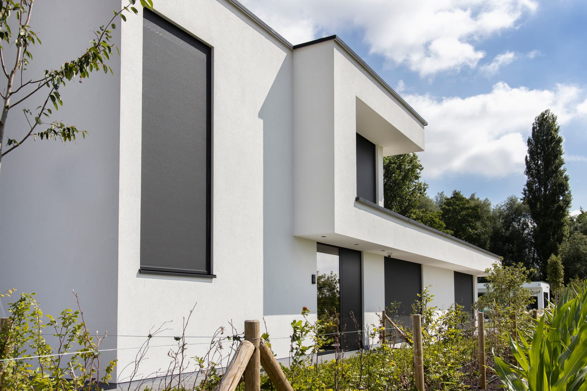 Wind‑resistant Brustor outdoor ZIP screens installed on a modern white home, providing effective sun protection and privacy on large façade windows